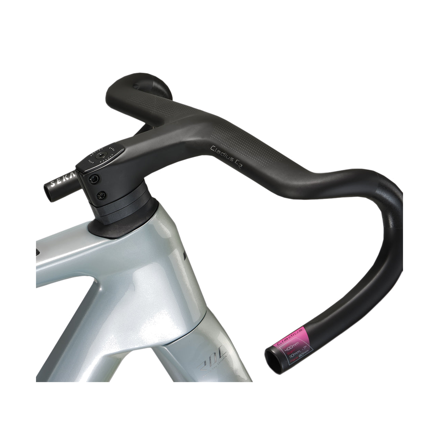Integrated carbon gravel handlebar and stem clamped to a bike head tube, flared drop sweeping to the right, micro-textured tops and a spec tag at the bar end