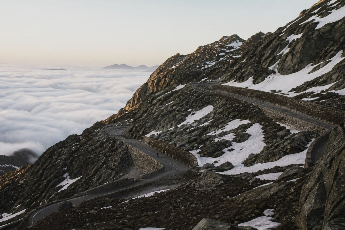 Empty switchback road on an alpine pass above a sea of cloud